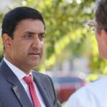 Sanders-Khanna Gambit Risks Revenue Backfire Two professionals engaged in conversation outdoors