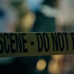 ICE Stop Chaos: Cameras Missing, Questions Explode Caution tape marking a crime scene with blurred figures in the background