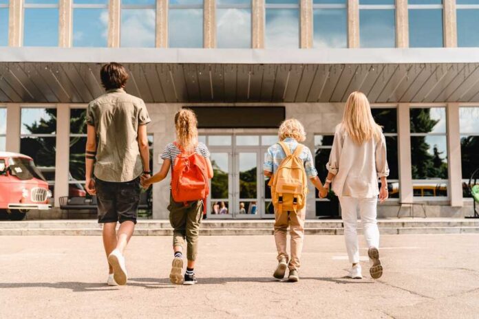 Young,Parents,Seeing,Their,Kids,Children,To,School,For,Lessons Students in a classroom raising their hands to answer a question