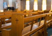 Worship Site Fires Surge — What’s Really Happening? Wooden church pew with carved cross in a sunlit sanctuary