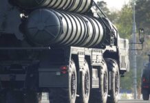 A military missile system positioned on a grassy field during sunset