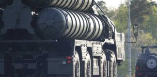 A military missile system positioned on a grassy field during sunset