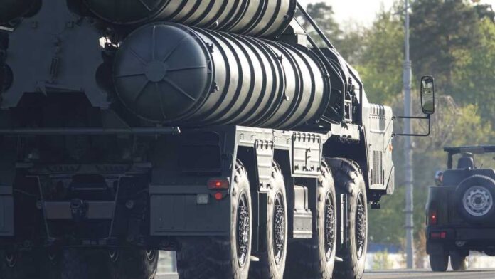A military missile system positioned on a grassy field during sunset