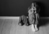 Gang Racket Exposed—Victims As Young As 14 Child sitting on floor with face in hands beside stuffed bunny