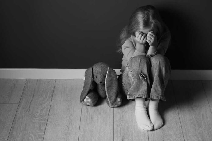 Upset,Little,Girl,With,Toy,Bunny,Near,Dark,Wall,Indoors, Child sitting on floor with face in hands beside stuffed bunny