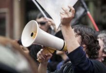 Mask Up: ACLU’s Anti-Tracking Guide Person holding megaphone at a protest rally.
