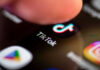 Beach Town Besieged — 400+ Arrests Finger tapping TikTok app on a smartphone screen
