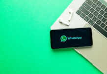 India Halts WhatsApp — What’s Meta Hiding? Smartphone on laptop with WhatsApp displayed alongside earbuds