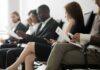 Job applicants seated in a waiting area reviewing documents