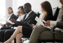 Job applicants seated in a waiting area reviewing documents
