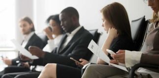 Job applicants seated in a waiting area reviewing documents