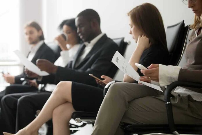 Job applicants seated in a waiting area reviewing documents