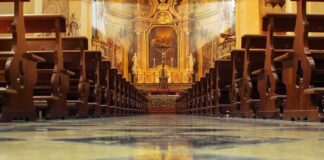 Church interior with wooden pews facing ornate altar
