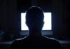 person silhouetted in front of a bright computer screen