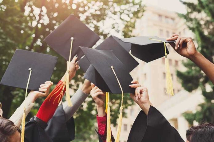 shutterstock_1064906966 Graduates raise mortarboards with tassels in celebration