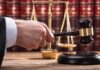 Judge's hand holding gavel near scales of justice