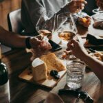 Bizarre Age Cutoff At Dinner Triggers Missouri Firestorm Hands toasting wine glasses over a cheese board