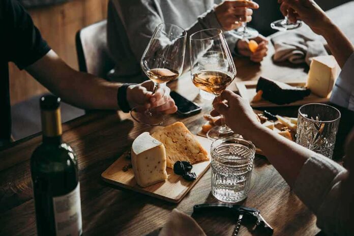 shutterstock_1081684592 Hands toasting wine glasses over a cheese board