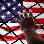 USS Lincoln Sailor Blindsided At Home Hand reaching through fence toward American flag