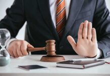 Judge with gavel raising hand in stop gesture
