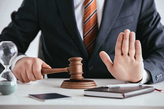 shutterstock_1283961133 Judge with gavel raising hand in stop gesture