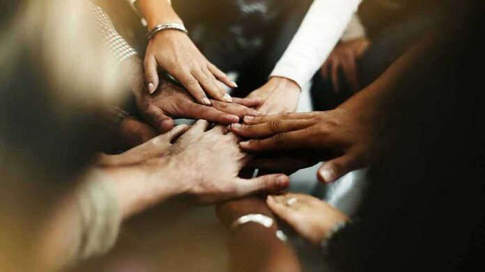 shutterstock_1331744636 Group hands stacked in a teamwork gesture