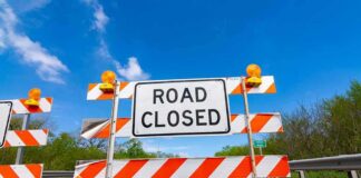 Road closed barricade with orange sandbags on a sunny day