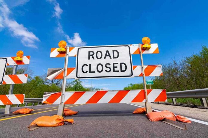 Road closed barricade with orange sandbags on a sunny day