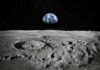 Moon surface with footprints and Earth rising over the horizon