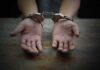 Hands in handcuffs on a wooden table