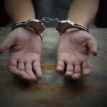 Premeditated Killer Freed — Parole Board Blinks Hands in handcuffs on a wooden table