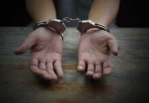 Hands in handcuffs on a wooden table
