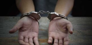 Hands in handcuffs on a wooden table