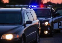 Near-Governor Nabbed: Meth Pipe Found? Police car with flashing lights behind a stopped vehicle at dusk