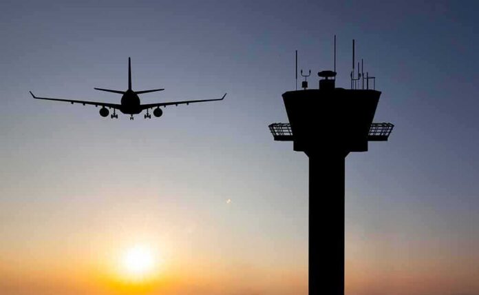 shutterstock_350063216 Airplane approaching runway near airport control tower at sunset