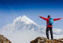 Bible Fight Erupts Over Everest Fossils Hiker with arms raised facing snowy mountain peak