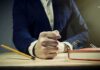 Man in suit slams fist on desk with flying paperclips