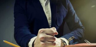 Man in suit slams fist on desk with flying paperclips