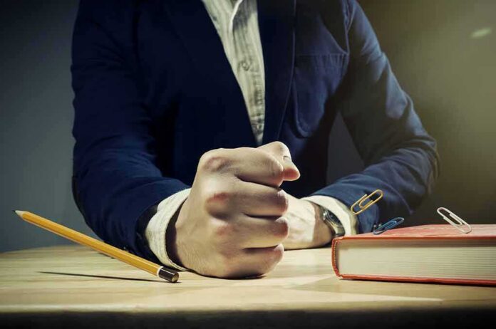 Man in suit slams fist on desk with flying paperclips