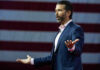 Optics Nightmare: Russian Money at Trump Jr.’s Wedding? Man speaking in front of American flag backdrop.