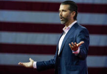 Optics Nightmare: Russian Money at Trump Jr.’s Wedding? Man speaking in front of American flag backdrop.