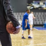 Backlash Erupts Over Teen Sophie Support Basketball coach in suit holding ball courtside