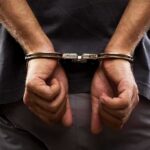 person with hands cuffed behind back