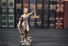 Lady Justice statue with scales in front of law books