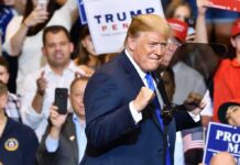 Donald Trump at a rally raising his fists on stage
