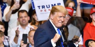 Donald Trump at a rally raising his fists on stage