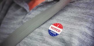 I voted sticker on a gray shirt under a seat belt