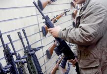 DOJ Intercepts Rifle Before Alleged ISIS Attack Person examining a black rifle in a gun store