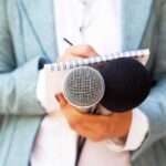 Journalist holding microphones and notepad