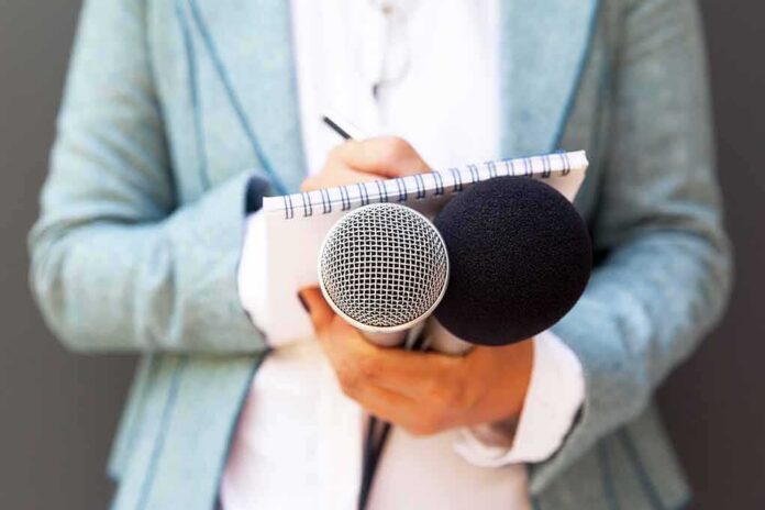 Journalist holding microphones and notepad